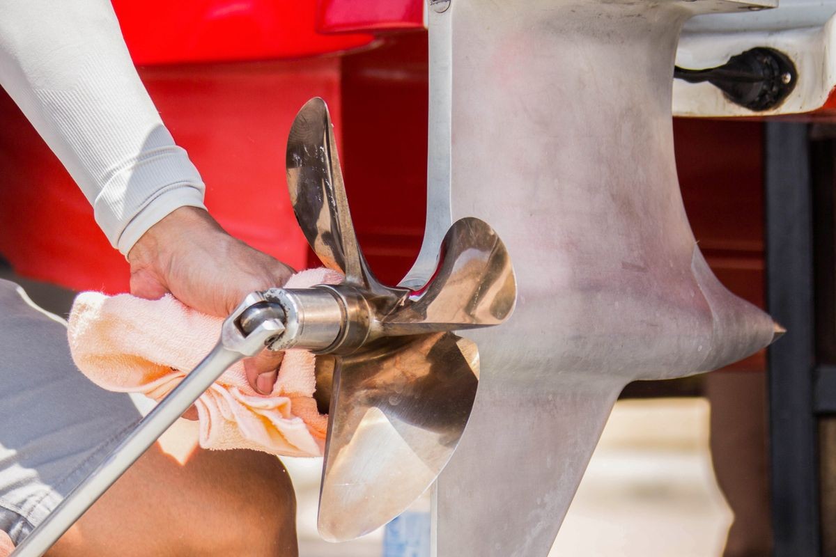 Close up image of four bladed stainless steel speed Boat Engine propeller,Men are checking the bolts.